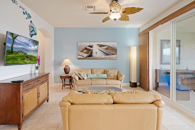 living area with ceiling fan, visible vents, arched walkways, light tile patterned floors, and baseboards