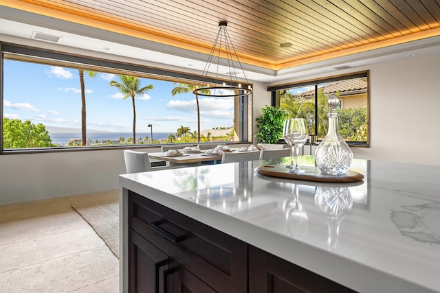 kitchen with wooden ceiling, an inviting chandelier, a raised ceiling, pendant lighting, and a water view