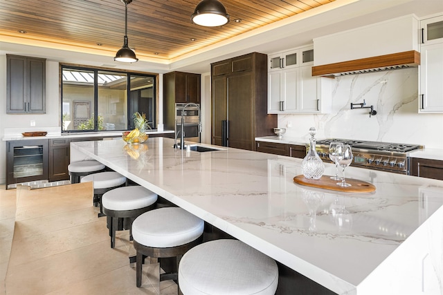 kitchen featuring wood ceiling, dark brown cabinetry, beverage cooler, white cabinetry, and hanging light fixtures