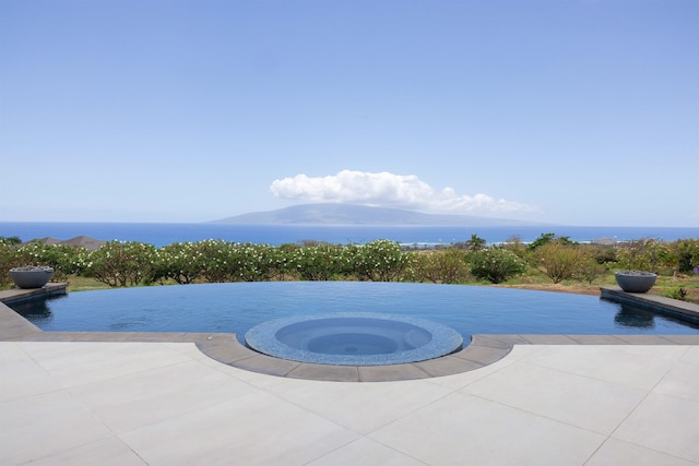 view of pool featuring an in ground hot tub and a water view