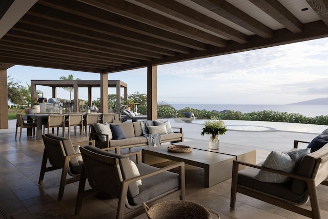 view of patio with a water view and an outdoor living space with a fire pit