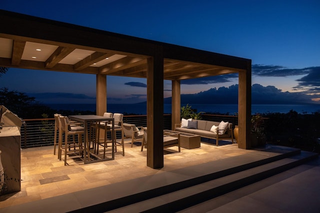 patio terrace at dusk with an outdoor living space, a balcony, and a water view