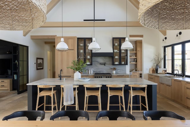 kitchen featuring a kitchen breakfast bar, a center island with sink, hanging light fixtures, and sink