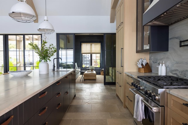 kitchen with light brown cabinets, ventilation hood, sink, high end stove, and decorative light fixtures