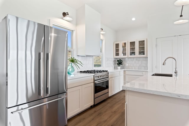 kitchen featuring decorative backsplash, sink, light stone countertops, appliances with stainless steel finishes, and white cabinets