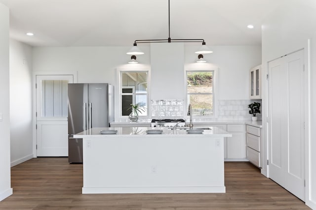 kitchen featuring white cabinetry, a kitchen island with sink, stainless steel refrigerator, pendant lighting, and sink