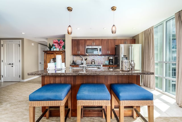 kitchen featuring backsplash, a wealth of natural light, decorative light fixtures, and stainless steel appliances