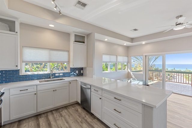 kitchen featuring dishwasher, sink, kitchen peninsula, white cabinets, and light wood-type flooring