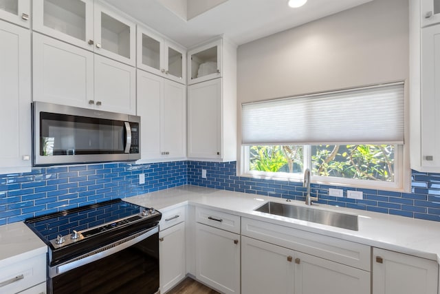 kitchen featuring sink, backsplash, white cabinetry, and electric stove