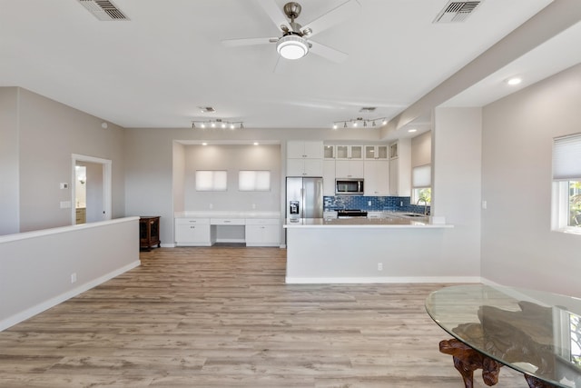 kitchen with kitchen peninsula, appliances with stainless steel finishes, decorative backsplash, sink, and white cabinetry