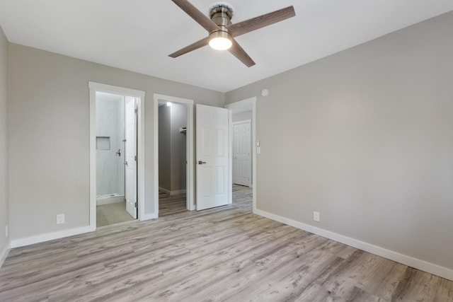 unfurnished bedroom with ceiling fan, a spacious closet, ensuite bathroom, light hardwood / wood-style floors, and a closet