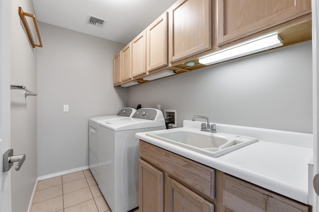 laundry area featuring cabinets, light tile patterned floors, sink, and washing machine and dryer