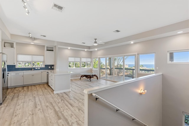 kitchen with white cabinetry, sink, ceiling fan, backsplash, and kitchen peninsula