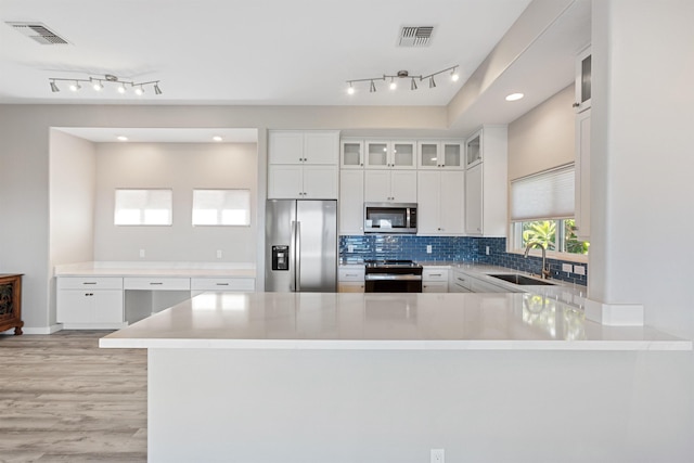 kitchen with kitchen peninsula, sink, white cabinets, and stainless steel appliances