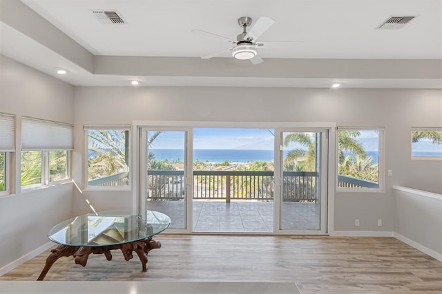 sunroom featuring a water view, plenty of natural light, and ceiling fan