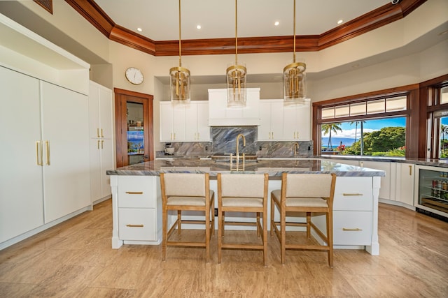 kitchen featuring a spacious island, white cabinetry, pendant lighting, and wine cooler