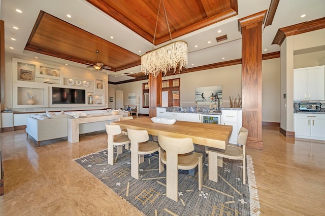 dining room featuring a towering ceiling, ornate columns, wood ceiling, ceiling fan with notable chandelier, and a raised ceiling