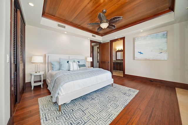 bedroom featuring connected bathroom, ceiling fan, dark hardwood / wood-style flooring, a tray ceiling, and wood ceiling