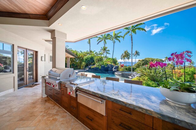 view of patio / terrace with grilling area, a water view, and an outdoor kitchen