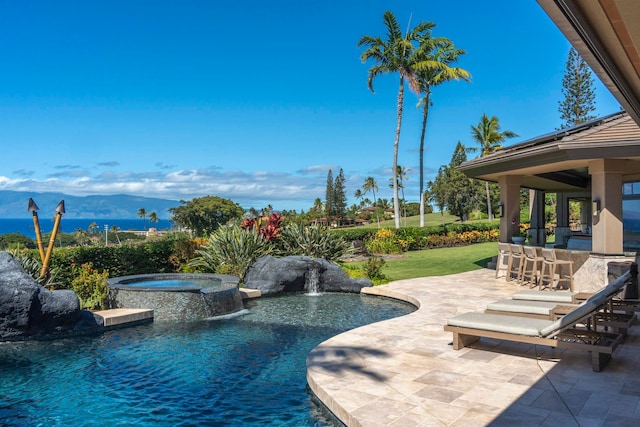 view of swimming pool featuring an in ground hot tub, pool water feature, a bar, a patio area, and a mountain view