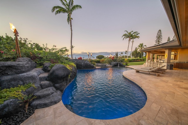 pool at dusk featuring a patio