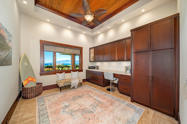 office area featuring a towering ceiling, a tray ceiling, ceiling fan, built in desk, and wooden ceiling