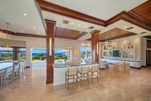 kitchen featuring pendant lighting, stone counters, ceiling fan with notable chandelier, a breakfast bar area, and decorative columns