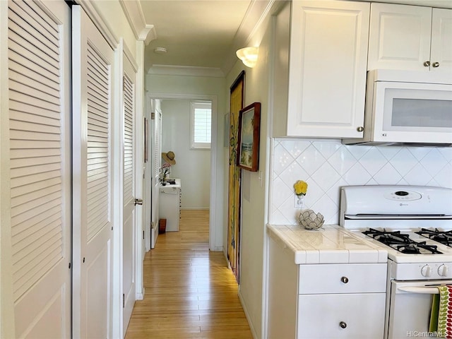 7146 Kamehameha V Hwy Unit 207C, Kaunakakai, HI 96748 - kitchen featuring white appliances, crown molding, tile counters, light wood-type flooring, and tasteful backsplash