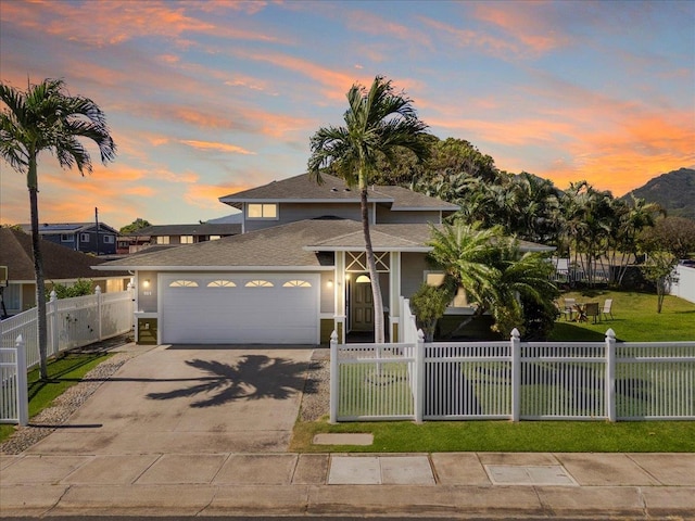 view of front of home with a fenced front yard, a front yard, concrete driveway, and an attached garage