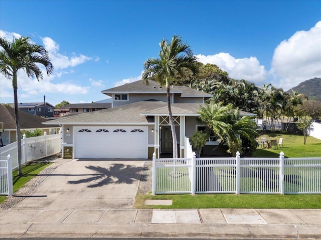 view of front facade featuring a fenced front yard, an attached garage, driveway, and a front yard