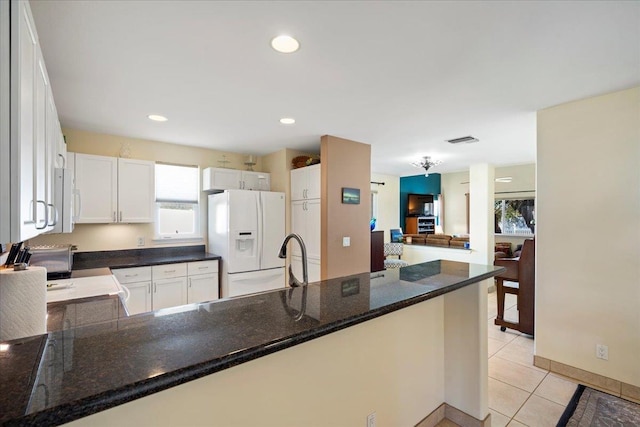 kitchen with visible vents, light tile patterned flooring, white cabinets, white fridge with ice dispenser, and open floor plan