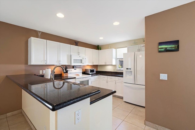 kitchen with white appliances, a peninsula, light tile patterned flooring, and white cabinetry