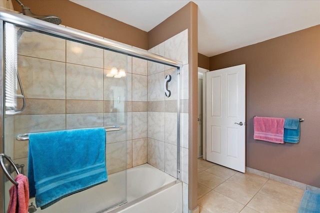 full bath featuring tile patterned flooring, baseboards, and bath / shower combo with glass door