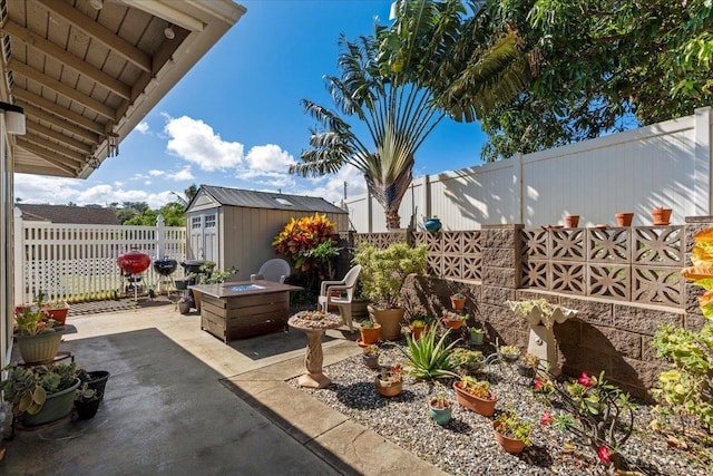 view of patio / terrace featuring an outdoor structure, a fenced backyard, an outdoor fire pit, and a shed