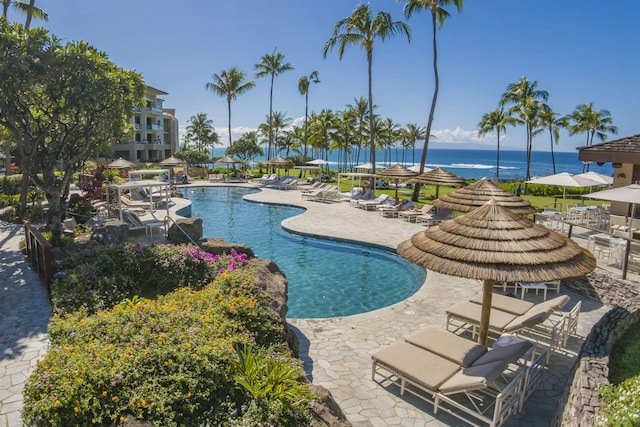 view of swimming pool featuring a water view and a patio