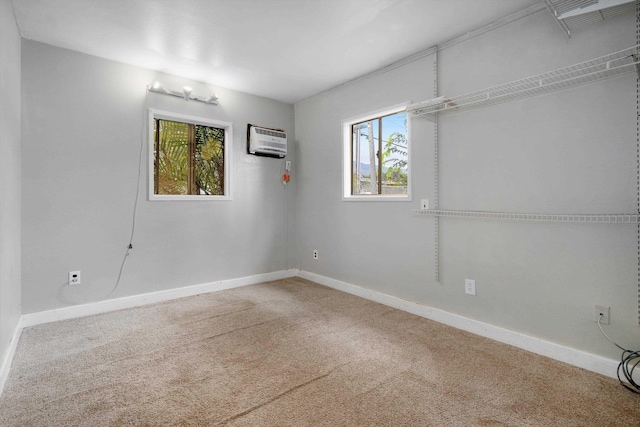 empty room with an AC wall unit and carpet flooring