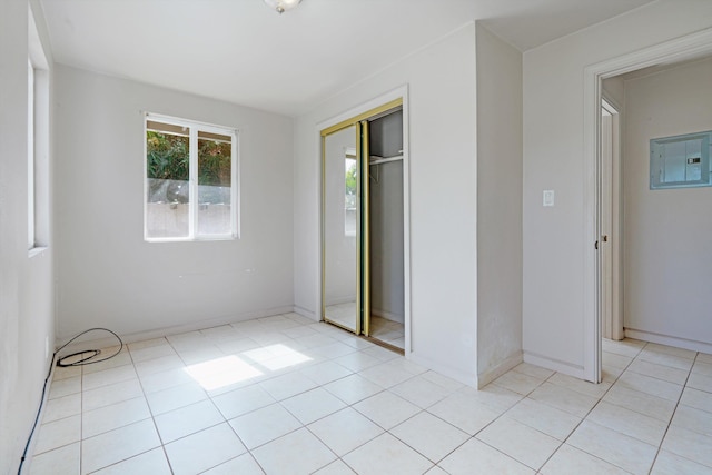 unfurnished bedroom featuring light tile patterned floors, electric panel, and a closet