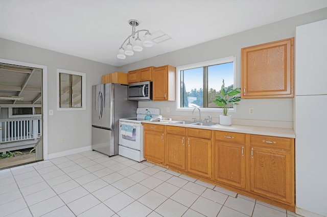 kitchen featuring appliances with stainless steel finishes, sink, light tile patterned floors, and decorative light fixtures