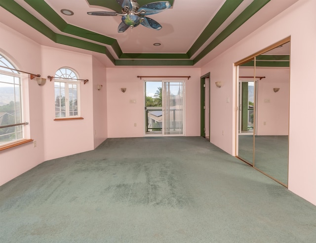 spare room featuring carpet, ceiling fan, a healthy amount of sunlight, and a tray ceiling