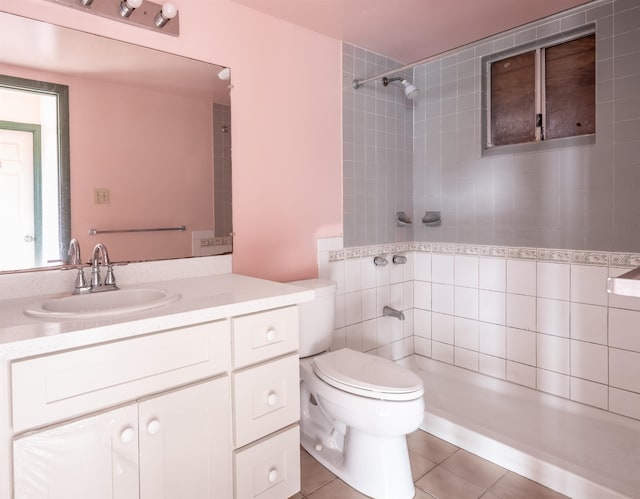 bathroom with tiled shower, vanity, tile patterned floors, and toilet