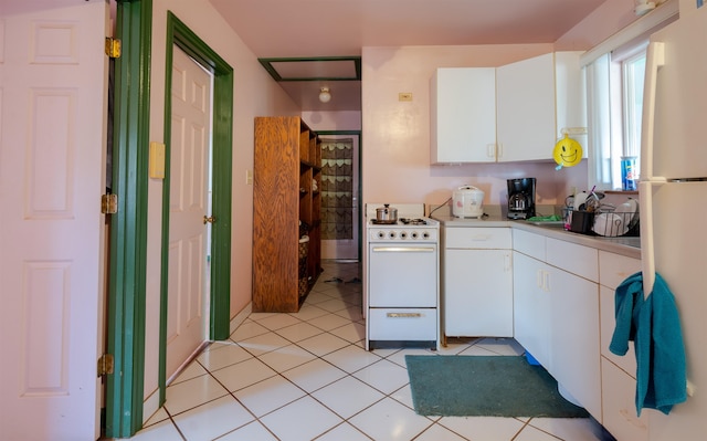 kitchen with light tile patterned floors, white cabinets, and white appliances