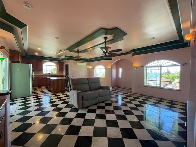 unfurnished living room featuring a tray ceiling and ceiling fan