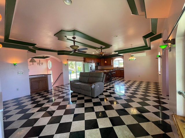 unfurnished living room featuring a tray ceiling and ceiling fan