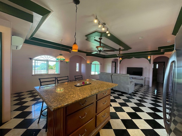 kitchen featuring ceiling fan, a center island, a kitchen breakfast bar, an AC wall unit, and pendant lighting