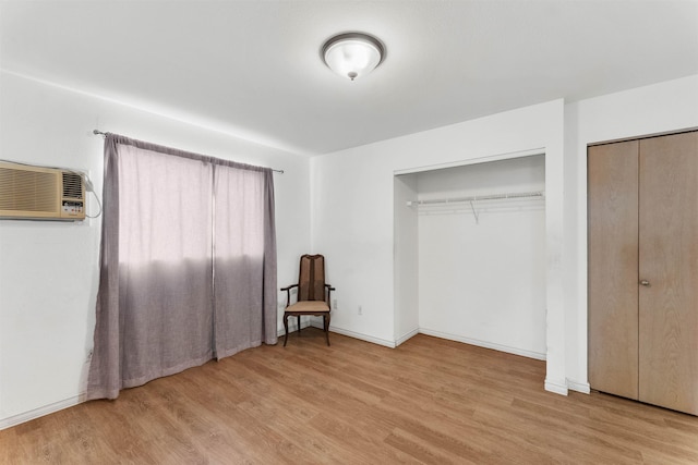 unfurnished bedroom featuring a wall mounted air conditioner and light wood-type flooring