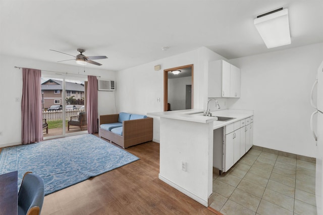 kitchen with sink, kitchen peninsula, white cabinets, and ceiling fan