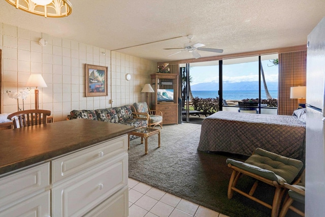 living room with a ceiling fan, light carpet, light tile patterned floors, a textured ceiling, and floor to ceiling windows