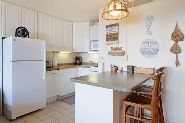 kitchen with white appliances, a peninsula, white cabinets, light tile patterned flooring, and a breakfast bar area