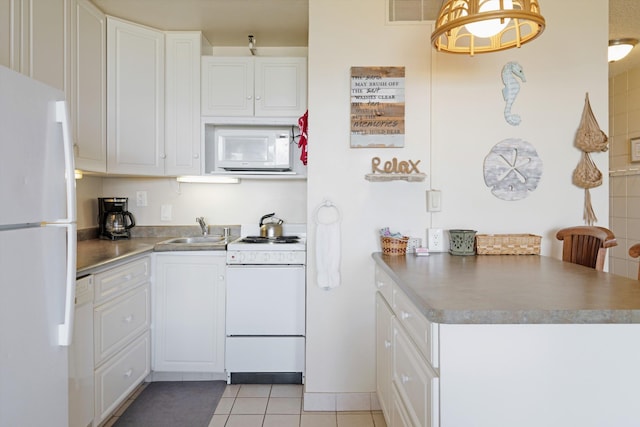 kitchen with white appliances, a sink, white cabinetry, a peninsula, and light tile patterned flooring