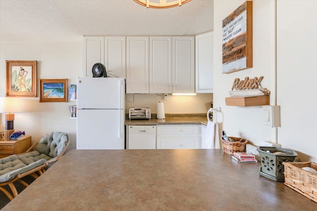 kitchen featuring white appliances, white cabinetry, dark countertops, and a textured ceiling